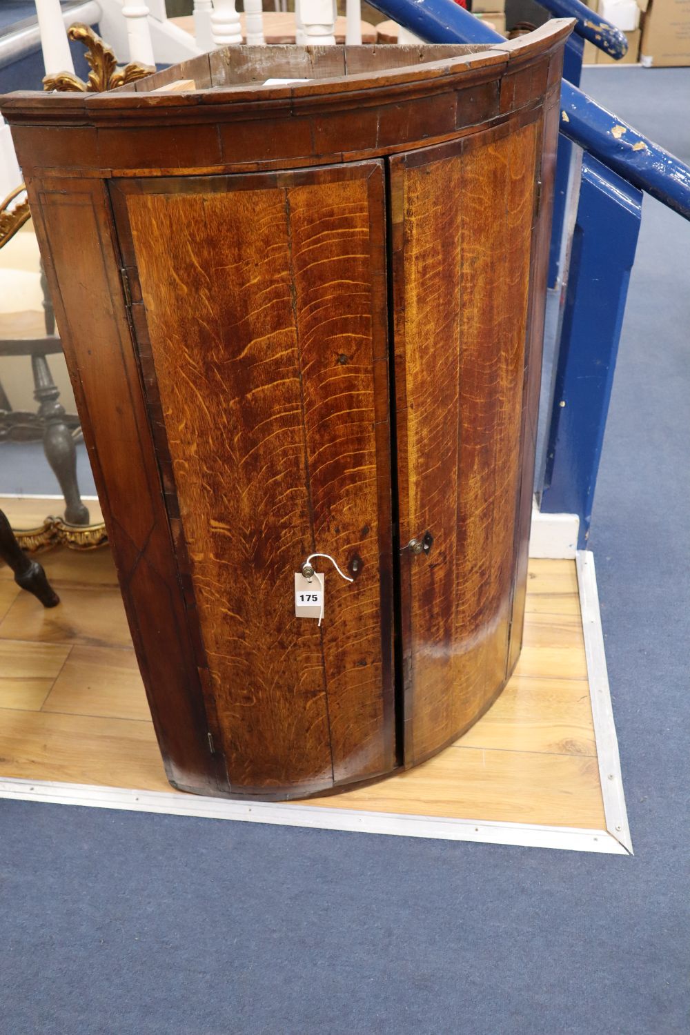 A George III oak bow-fronted hanging corner cupboard, mahogany-banded, width 64cm
